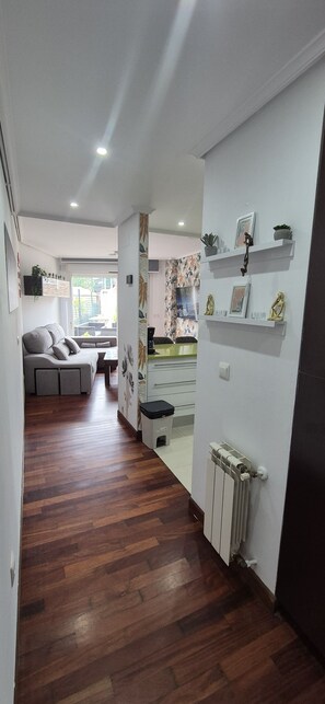A hallway with wooden flooring, a radiator, and white walls.