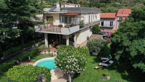 Ein zweistöckiges Haus mit Balkon, Schwimmbad und Garten.
