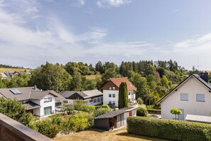A residential area with houses, a clear sky, and a hilly landscape in the background.