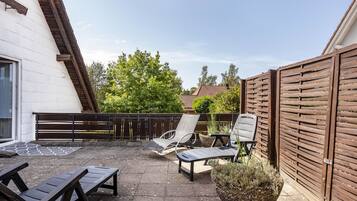 A patio with two lounge chairs, a small table, and a potted plant.