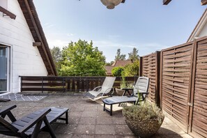 A patio with two lounge chairs, a small table, and a potted plant. - Apartment 'Auszeit' with Private Terrace, Private Garden and Wi-Fi (Niedereschach)