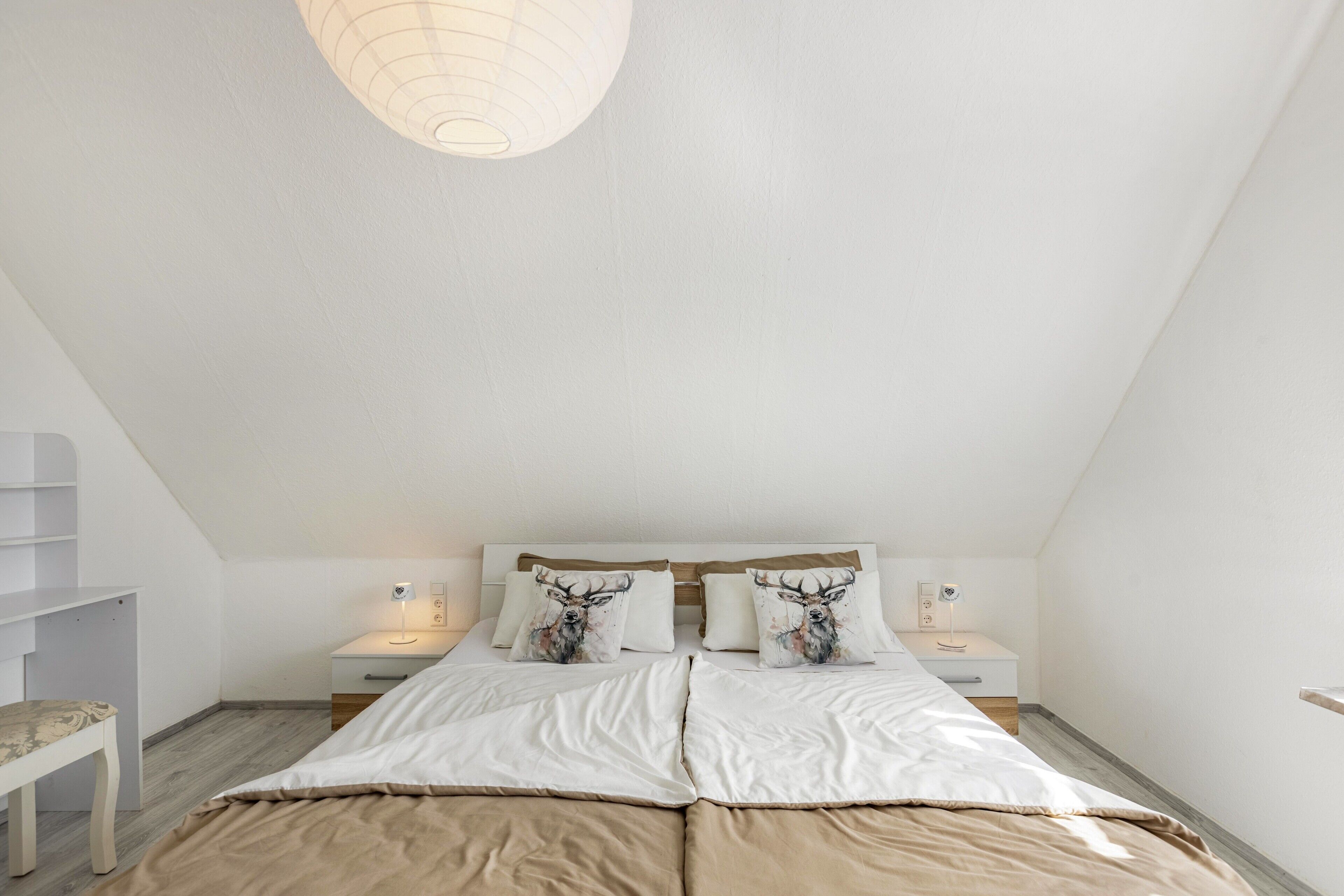 A bedroom with a bed, two bedside tables, a nightstand, and a lamp.
