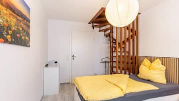 A bedroom with a bed, a bedside table, a lamp, and a painting on the wall.
