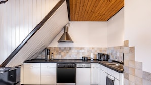 A modern kitchen with white cabinetry, a black dishwasher, a stove, and a wooden ceiling.