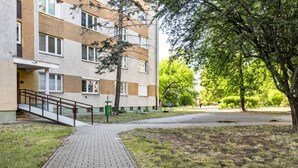 En byggnad med flera våningar, med en gångstig av tegelstenar som leder till en trappa. Byggnaden är omgiven av gräs och träd.