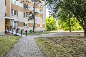 Monikerroksinen rakennus, jonka edessä on tiilestä tehty polku, joka johtaa portaikkoon. Rakennuksen ympärillä on nurmikkoa ja puita.