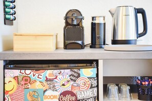 Een keukenblad met een koffiezetapparaat, een waterkoker en een koelkast met een kleurrijk stickerontwerp.