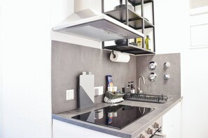 Una cucina moderna con piano cottura integrato, lavello e un piccolo spazio contenitore sopra il bancone.