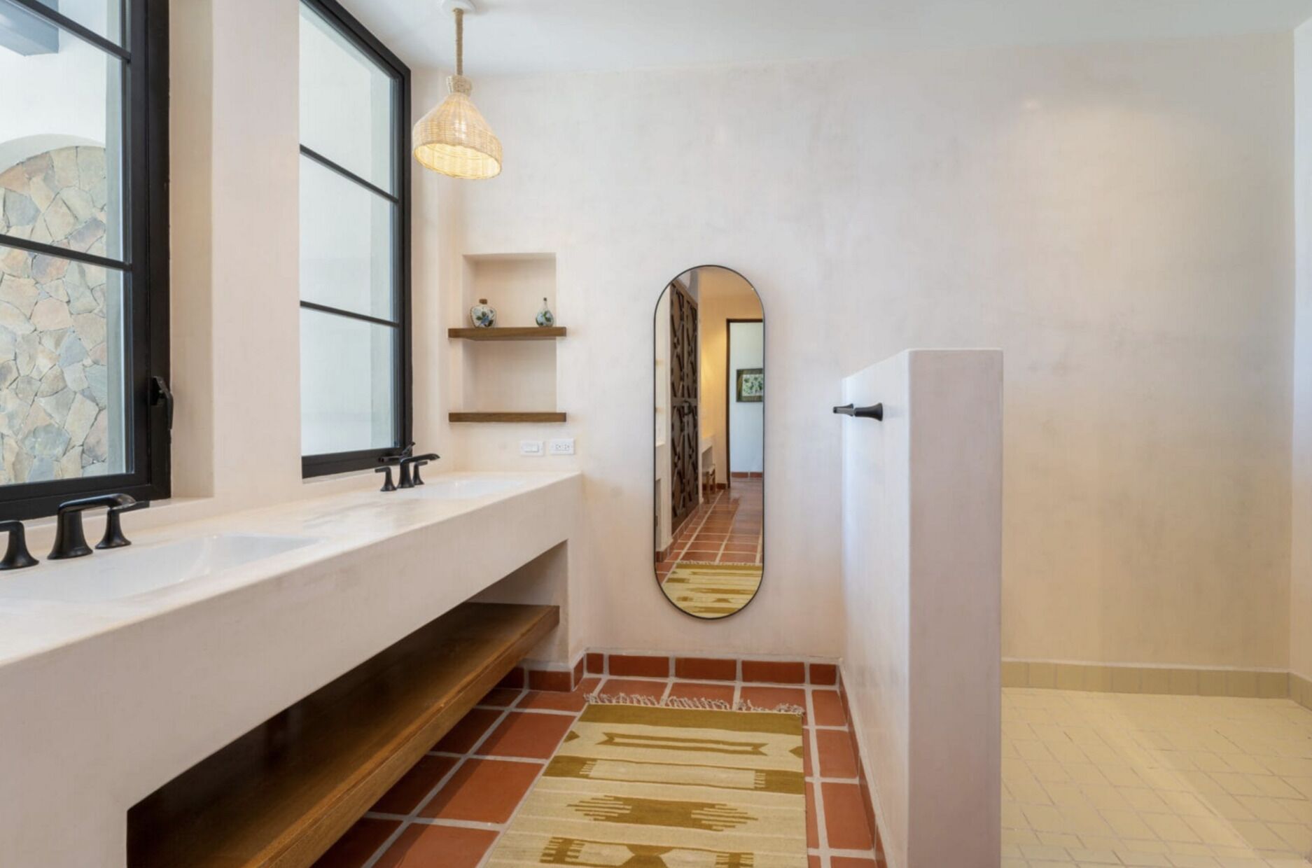 Un baño con un espejo grande, un lavabo blanco y una lámpara colgante.