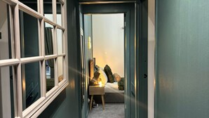 A narrow hallway with a bed at the end, a nightstand, and a lamp. - Cope Corner (Walsall)