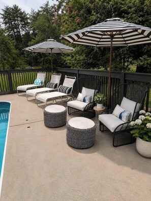 A poolside area with lounge chairs, striped umbrellas, and round ottomans. - 6BR Pool + Hot Tub + Pet fence + Fire pit + 2 acre (Huntsville)