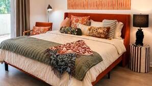 Una camera da letto con un grande letto, un lampadario, un’opera d’arte a parete e una lampada da comodino.