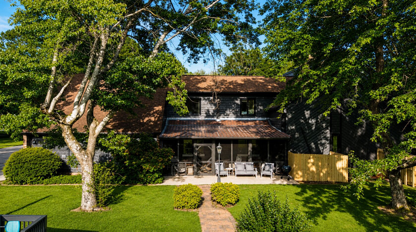 A two-story house with a covered patio area, a brick exterior, and a well-maintained lawn.