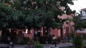 Un bâtiment à la façade rose, doté d’un patio couvert et agrémenté d’une petite cascade dans le jardin.