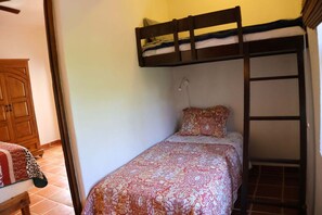 Una cama individual con cabecera de madera, una colcha estampada y una almohada.