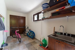 Una cocina con un lavamanos, armarios, una bicicleta y una puerta.