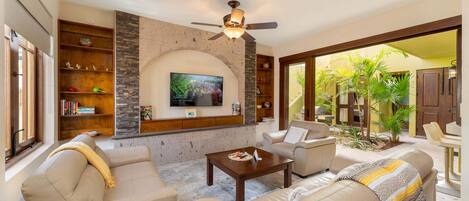 A living room with a TV, sofas, a coffee table, and a ceiling fan.