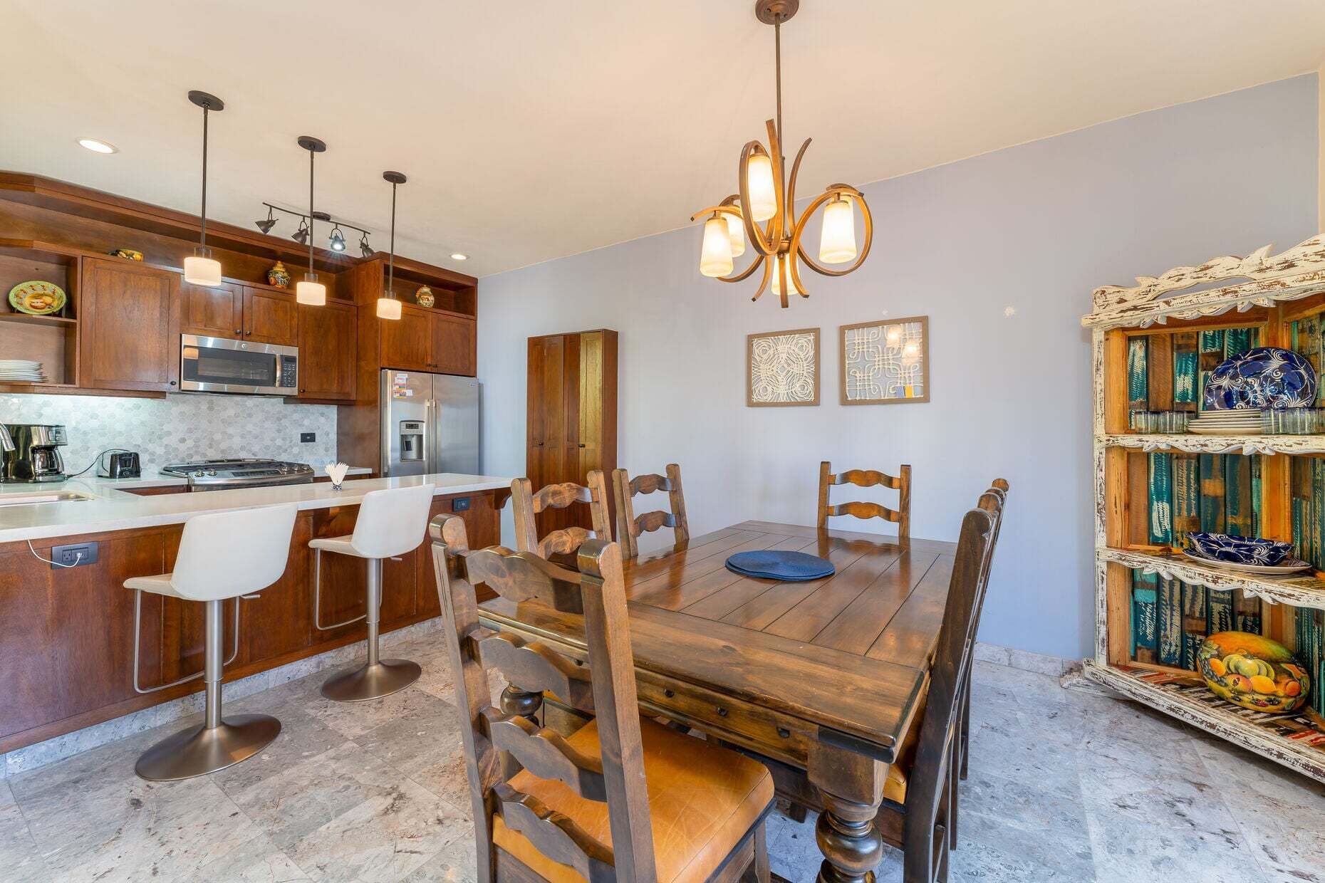 Una cucina con mobili in legno, un frigorifero in acciaio inossidabile e un'area pranzo con tavolo e sedie in legno.