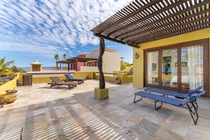 Una terraza con sillones, mesa de billar y vista al mar.