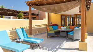Eine Terrasse im Freien mit einer Pergola, Liegestühlen, einem Tisch und einer Sitzecke.