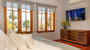 Ein Schlafzimmer mit einem Bett, zwei Fenstern mit Jalousien, einem Fernseher an der Wand und einem Holzschrank.