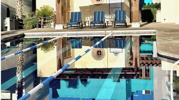 Una piscina con sillas de descanso y una zona de estar cubierta.