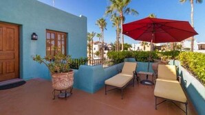 A patio with lounge chairs, a red umbrella, and a potted plant. - Cozy Home a few Steps From Community Pool (  Loreto)