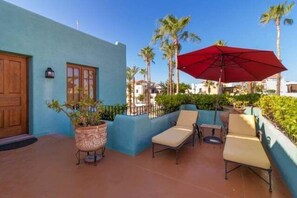 A patio with lounge chairs, a red umbrella, and a potted plant. - Cozy Home a few Steps From Community Pool (  Loreto)