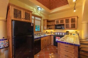 A kitchen with wooden cabinets, a black refrigerator, a tiled backsplash, and a wooden ceiling. - Cozy Home a few Steps From Community Pool (  Loreto)