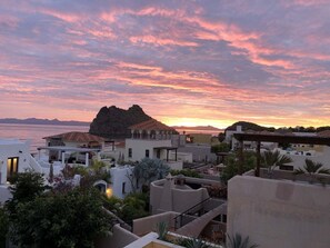 A coastal town with buildings, a prominent rock formation, and a sunset view. - Beautiful Custom Home. Amazing Ocean View (  Loreto)