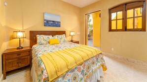 A bedroom with a bed, two bedside lamps, a ceiling fan, a painting, and a window. - Beautiful Custom Home. Amazing Ocean View (  Loreto)