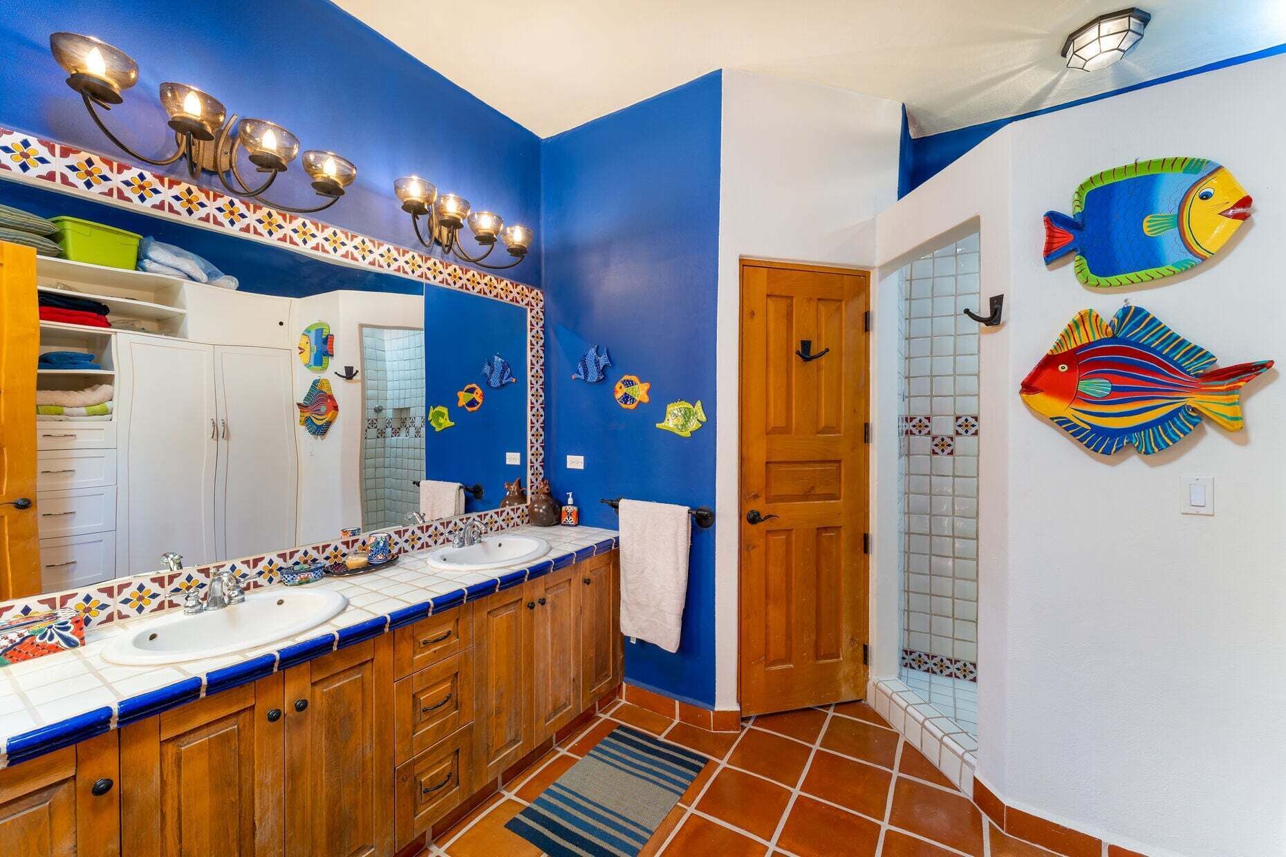 Un baño con dos lavabos, un espejo y decoración de peces en la pared.