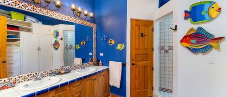 Un baño con dos lavabos, un espejo y decoración de peces en la pared.