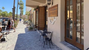 Un bâtiment dont l’entrée est pavée de pierres, avec une porte en bois et une enseigne.