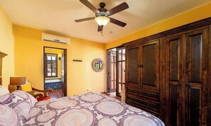 Ein Schlafzimmer mit Bett, Deckenventilator, Klimaanlage, Holzschrank und Fenster mit Blick.