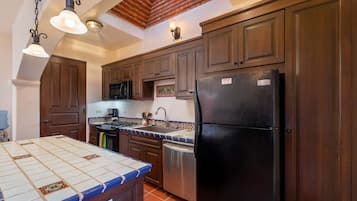 Una cocina con armarios de madera, un refrigerador negro, una estufa y un microondas.