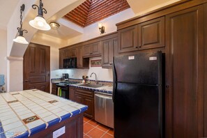 A kitchen with wooden cabinets, a black refrigerator, a stove, and a microwave. - Welcome to Casa Sonrisas, a Charming and Peaceful Retreat (  Loreto)