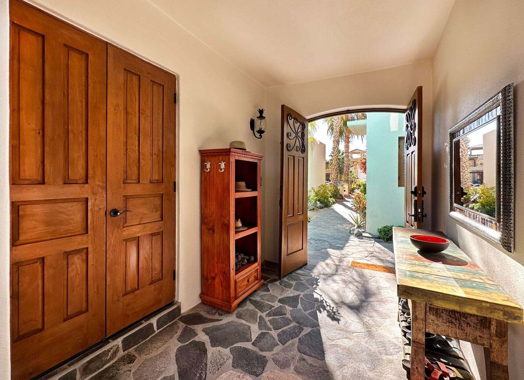 A hallway with wooden doors, a cabinet, and a table with a bowl.