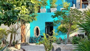 A turquoise building with a covered patio, surrounded by lush greenery and a stone pathway. - Newly Renovated Home- 5 Steps From LAP Pool (  Loreto)