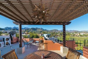 Un patio techado al aire libre con vistas a montañas, una antena parabólica y mobiliario exterior.