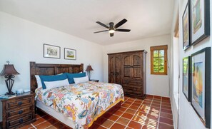 A bedroom with a bed, a wooden wardrobe, a ceiling fan, and artwork on the walls. - Discover This Charming 2-bedroom Home Located in Founders Area! (  Loreto)