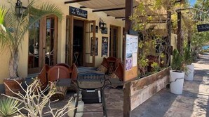 A covered outdoor seating area with tables and chairs, a sign reading "Le Bistro," and potted plants. - Discover This Charming 2-bedroom Home Located in Founders Area! (  Loreto)