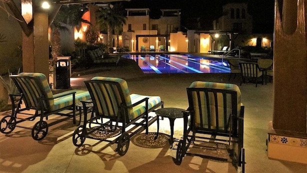 Zona de piscina al aire libre con sillones de descanso y un área de estar cubierta.