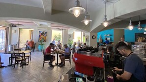 Un interior de restaurante con mesas, sillas, luces colgantes y