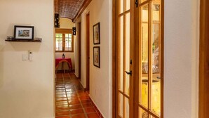 A hallway with a tiled floor, a wooden door with glass panels, and a red table with a chair. - Ideal Home, Perfect Location in Loreto Bay, Steps From the Beach With Private Pool. By Casago (  Loreto)