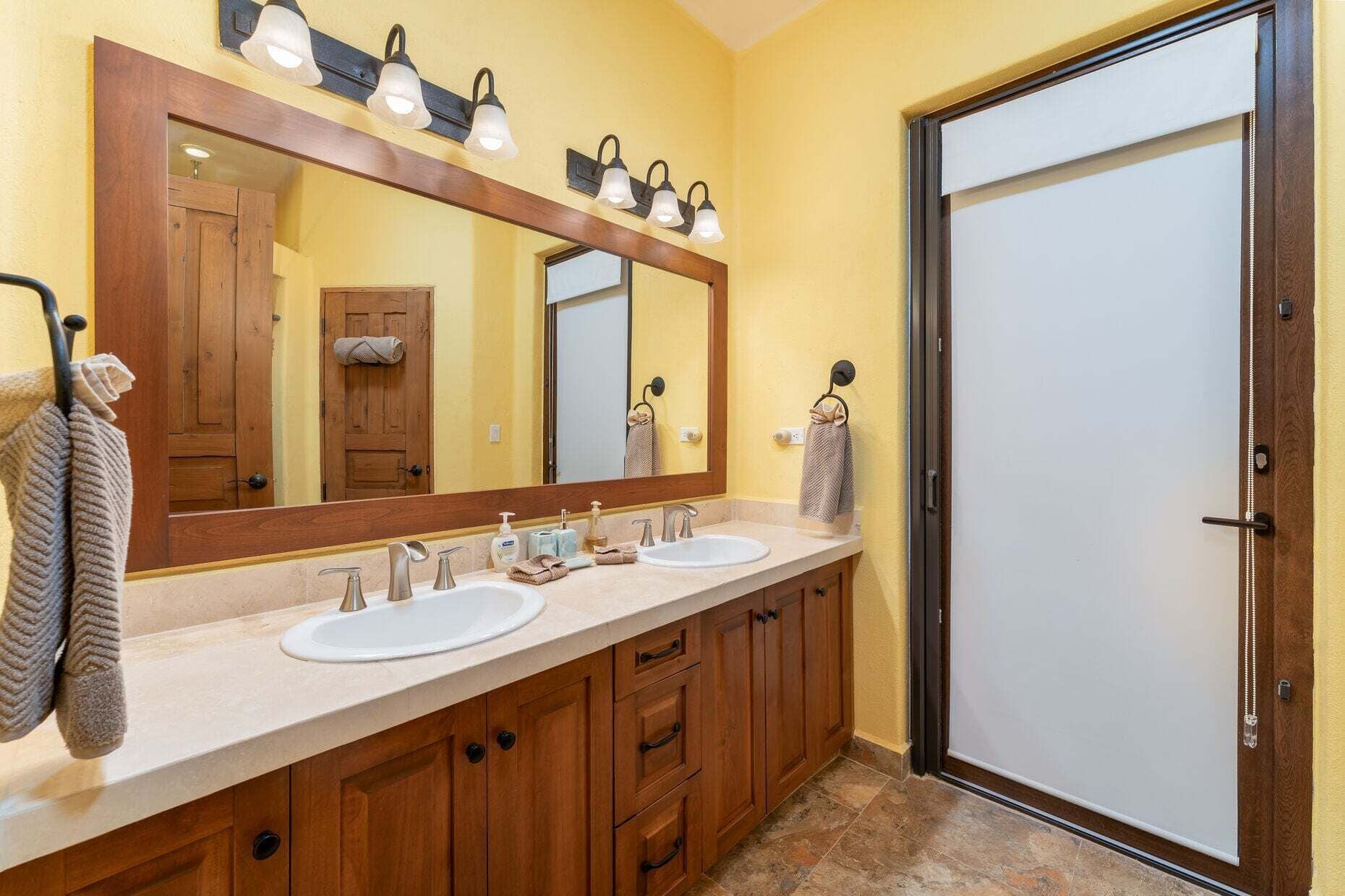 A bathroom with two sinks, a large mirror, and wooden cabinets.