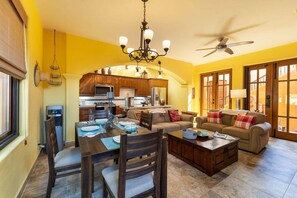 Amplia sala de estar con comedor y cocina al fondo, además de un ventilador de techo.
