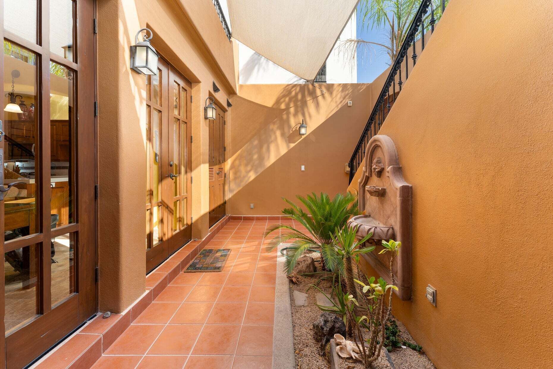 A corridor with a tiled floor, wooden doors, and a wall-mounted water feature.