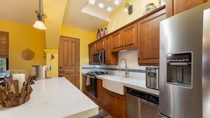 A modern kitchen with wooden cabinets, stainless steel appliances, and a white countertop. - Wonderful Home Next to the Community Pool (  Loreto)