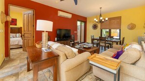 A living room with a sofa, TV, dining table, and ceiling fan. - Wonderful Home Next to the Community Pool (  Loreto)